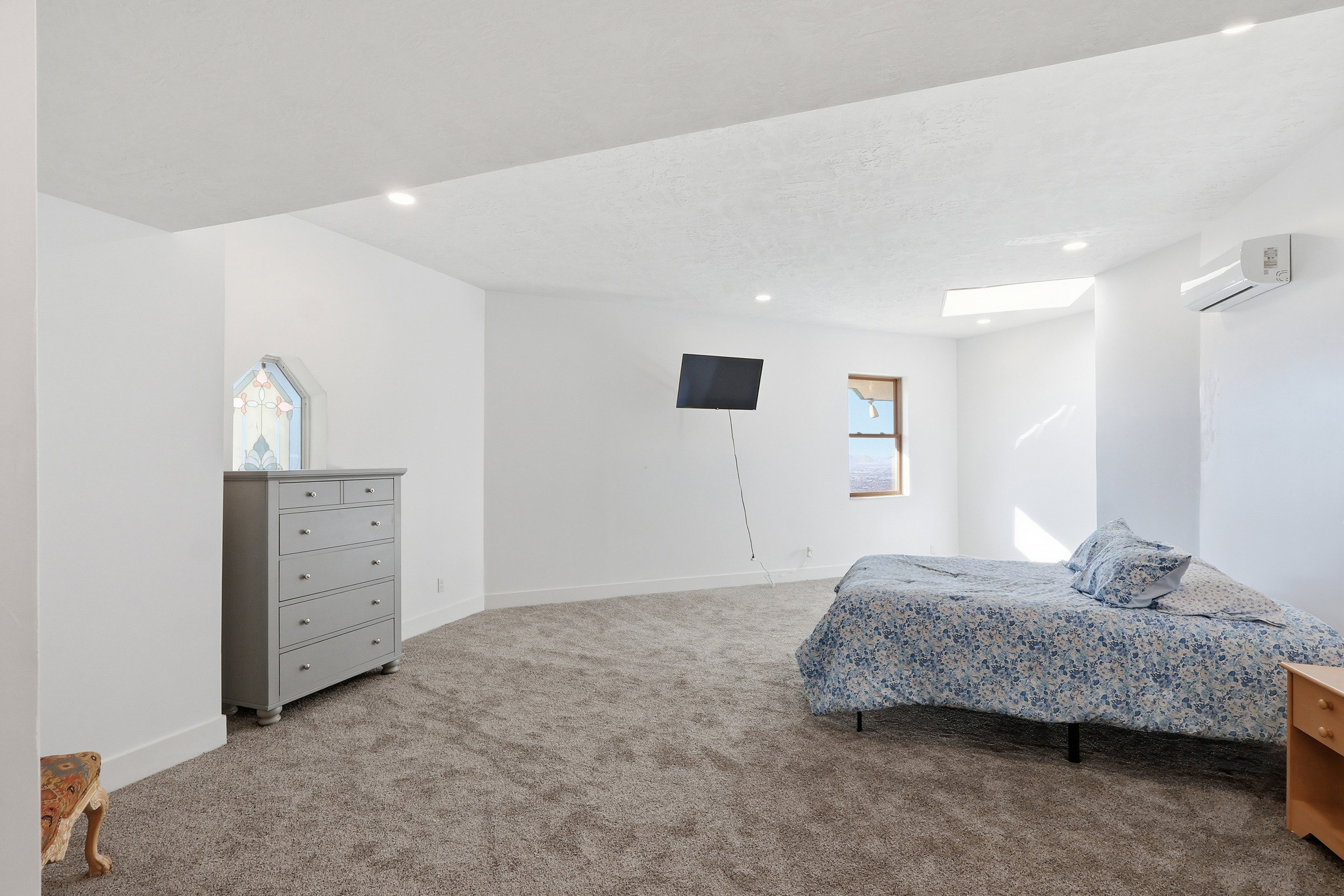 Bedroom with light carpet, a wall mounted air conditioner, recessed lighting, and a textured ceiling
