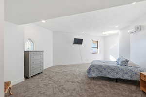 Bedroom with light carpet, a wall mounted air conditioner, recessed lighting, and a textured ceiling