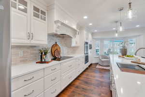 Kitchen with white cabinets, glass insert cabinets, decorative light fixtures, ornamental molding, and recessed lighting