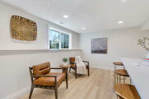 Sitting room with light wood-type flooring and recessed lighting