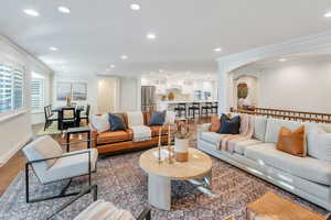Living area with arched walkways, crown molding, recessed lighting, and wood finished floors