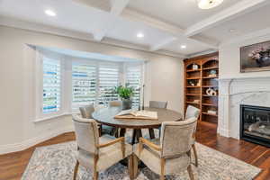 Dining room featuring coffered ceiling, beam ceiling, recessed lighting, a high end fireplace, and dark wood-style flooring