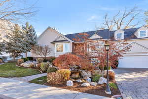 View of front of home featuring decorative driveway, a garage, and a front lawn