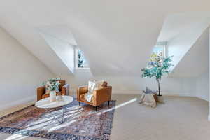 Sitting room featuring healthy amount of natural light, carpet, and vaulted ceiling