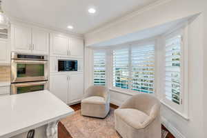Kitchen featuring white cabinets, stainless steel double oven, dark wood finished floors, light stone counters, and recessed lighting