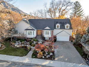 View of front of house with decorative driveway, brick siding, a front lawn, and a shingled roof