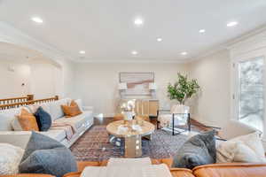 Living room with arched walkways, wood finished floors, recessed lighting, and crown molding
