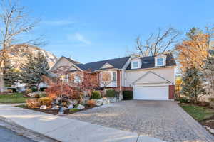 View of front of home featuring decorative driveway, a garage, brick siding, and a mountain view