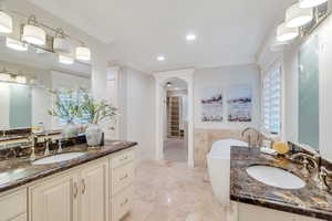 Full bath featuring a soaking tub, ornamental molding, two vanities, and a spacious closet