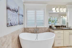 Bathroom with a wainscoted wall, tile walls, vanity, a soaking tub, and healthy amount of natural light