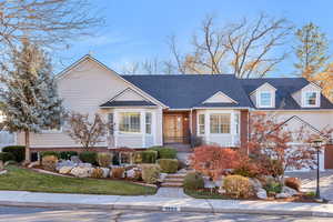 View of front facade with brick siding, roof with shingles, a garage, and a front lawn
