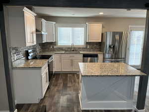 Kitchen featuring stainless steel appliances, white cabinets, light stone counters, and recessed lighting