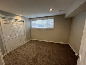 Unfurnished bedroom with dark carpet, a closet, and recessed lighting
