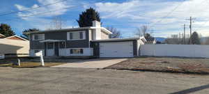 Split foyer home featuring driveway, an attached garage, and a chimney