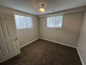 Spare room with dark colored carpet and baseboards