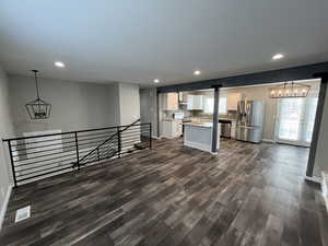 Unfurnished living room with a chandelier, dark wood-style floors, and recessed lighting