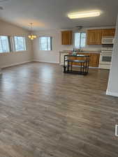 Kitchen with light countertops, white appliances, brown cabinets, and dark wood-type flooring