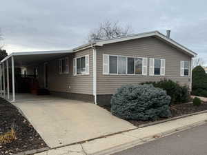 View of the covered parking, low-maintenance landscaping, and abundant windows of the home.