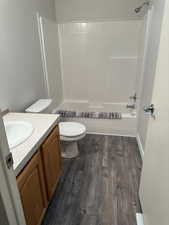 Full bathroom with vanity, dark wood-style floors, shower / bath combination, and a textured wall
