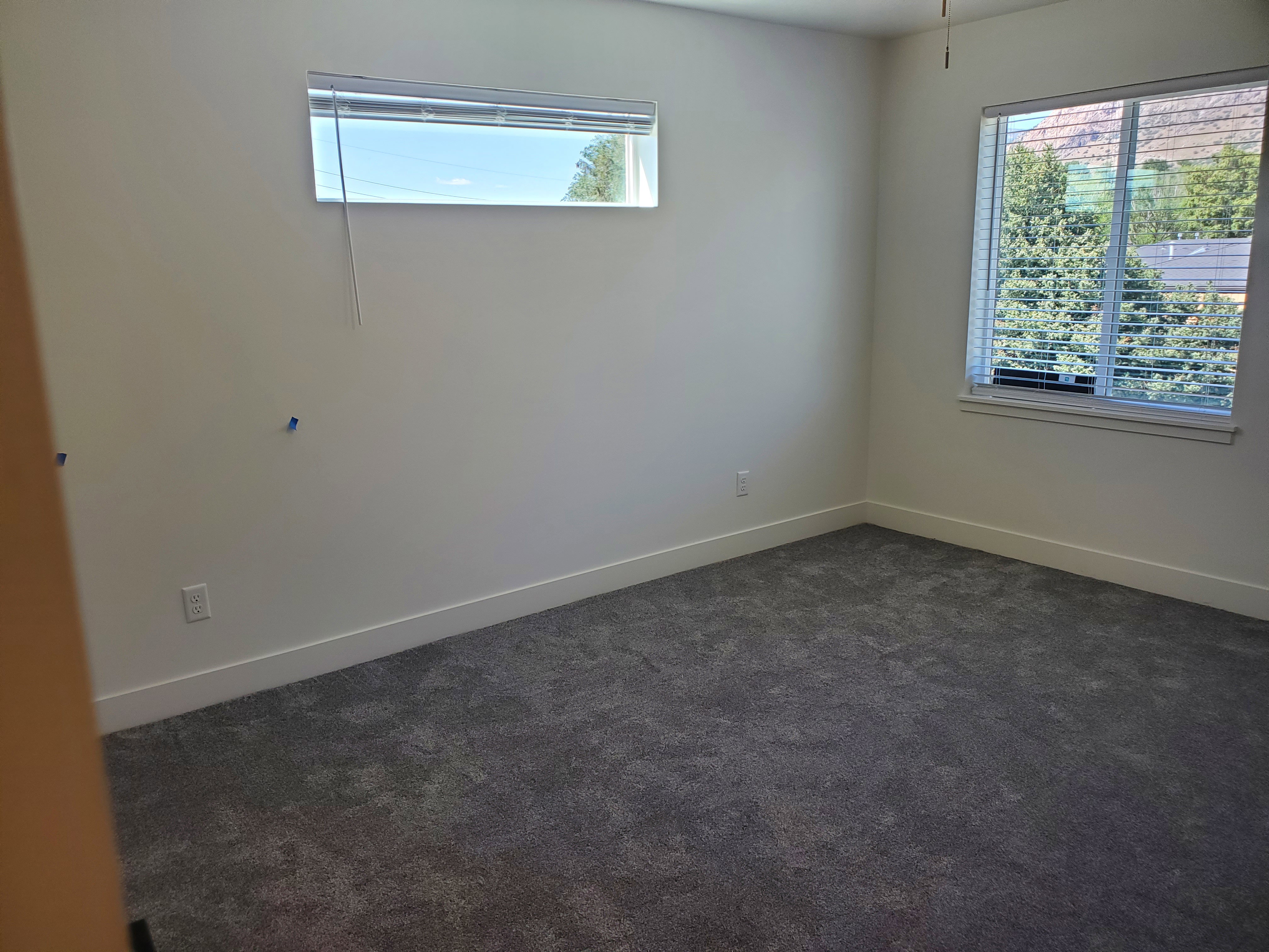 Empty room with dark colored carpet and baseboards