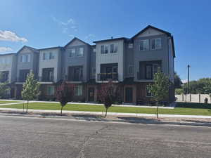 View of front of property featuring a front lawn, a residential view, board and batten siding, and a balcony