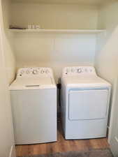 Laundry area featuring wood finished floors and washing machine and clothes dryer