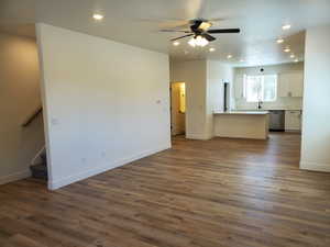 Unfurnished living room featuring recessed lighting, stairs, dark wood-type flooring, and ceiling fan