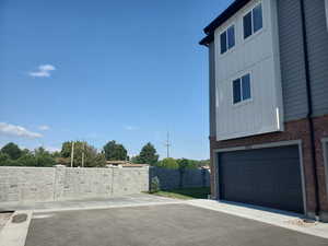 View of side of property featuring board and batten siding, brick siding, a garage, and driveway