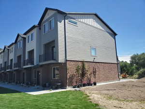 View of home's exterior featuring a balcony, board and batten siding, a residential view, a yard, and brick siding