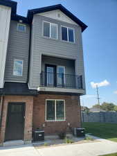 View of front of property featuring a balcony, brick siding, and a metal roof