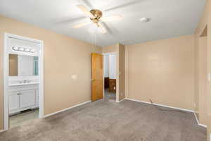 Unfurnished bedroom featuring light colored carpet, ceiling fan, and ensuite bathroom