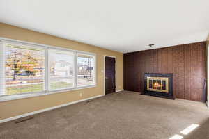 Unfurnished living room featuring an accent wall, a tiled fireplace, and carpet flooring
