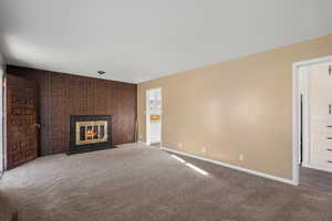 Unfurnished living room with a tile fireplace, carpet floors, and an accent wall