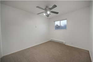Carpeted spare room with baseboard heating and a ceiling fan