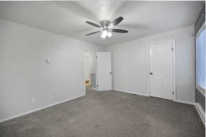 Unfurnished bedroom with a textured ceiling, a baseboard heating unit, dark carpet, and a ceiling fan