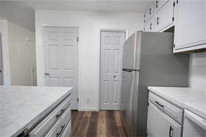Kitchen with light countertops, range, dark wood-style flooring, white cabinetry, and freestanding refrigerator