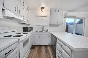 Kitchen featuring electric range, under cabinet range hood, light countertops, a peninsula, and a textured ceiling