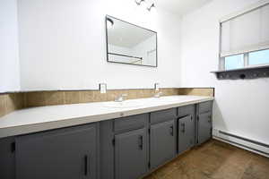 Full bath with a baseboard heating unit and double vanity
