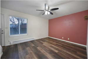 Empty room featuring a baseboard heating unit, dark wood-type flooring, a textured ceiling, and a ceiling fan