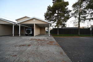 View of side of home featuring concrete driveway and an attached carport