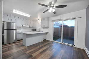 Kitchen featuring light countertops, stainless steel appliances, a peninsula, a baseboard heating unit, and a textured ceiling