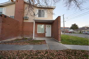 Doorway to property featuring brick siding and a yard