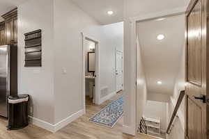 Corridor featuring recessed lighting, light wood-style flooring, and an upstairs landing