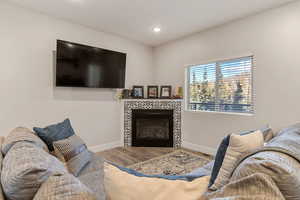 Living room with wood finished floors, a fireplace, and recessed lighting