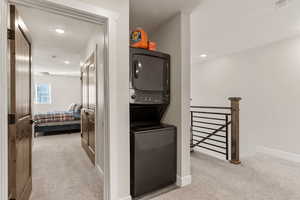 Hall with light carpet, recessed lighting, and stacked washer and clothes dryer