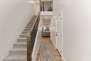 Staircase featuring a high ceiling, wood finished floors, and recessed lighting