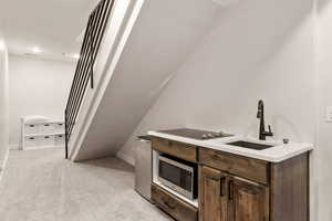 Bar with dark brown cabinets, light colored carpet, stainless steel microwave, black electric cooktop, and recessed lighting