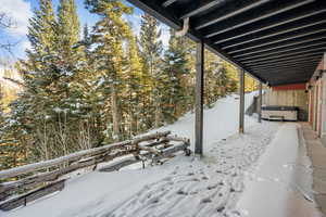 Snow covered patio featuring a hot tub