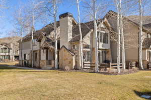 Rear view of property with stone siding, a yard, a chimney, and a residential view
