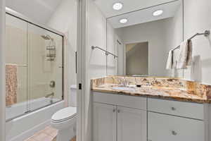 Bathroom featuring shower / bath combination with glass door, vanity, and light tile patterned floors